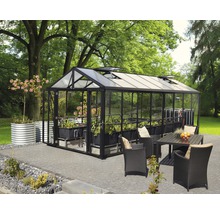 Kas met planten, tafel en stoelen in de tuin