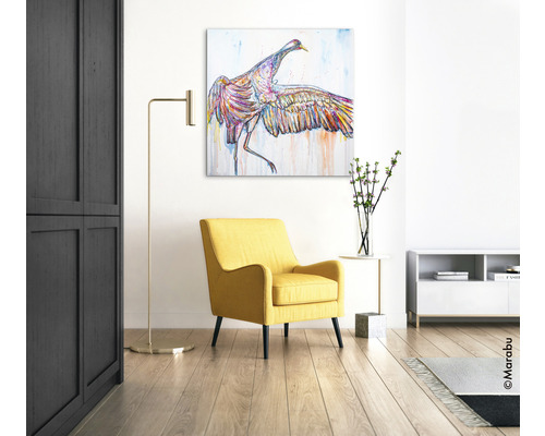 Woonkamer met gele fauteuil, staande lamp en schilderij van een vogel aan de muur