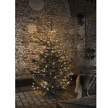 Kerstboom met lichtjes voor een bakstenen muur