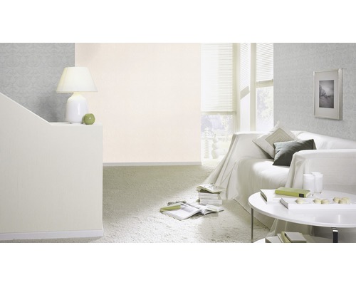 Woonkamer met bank, tafel, lamp en patroonbehang