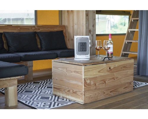 Interieurbeeld met kachel, wijnfles en wijnglazen op een houten tafel naast een zithoek