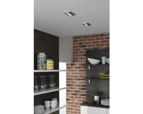 Keukenscène met plafondspots, bakstenen muur en open planken met servies