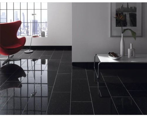 Woonkamer met glanzend zwarte vloertegels, fauteuil, tafel en raam