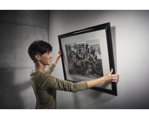 Vrouw houdt een ingelijste kunstdruk tegen een muur