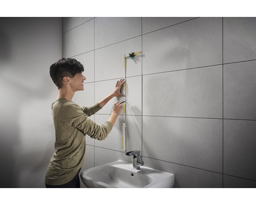 Vrouw meet muur met rolmaat in badkamer