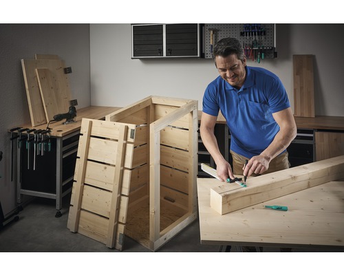 Man bouwt een houten kist in een werkplaats.