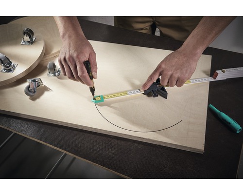 Een persoon tekent met een passer en een pen een halve cirkel op een houten plank. Meubelwielen bevinden zich ook op het bord.