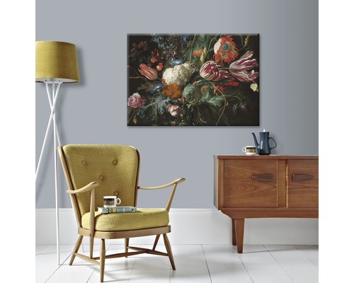 Schilderij met bloemstuk boven een houten buffetkast met fauteuil en vloerlamp