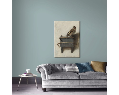 Canvas schilderij met vogelmotief boven een grijze bank