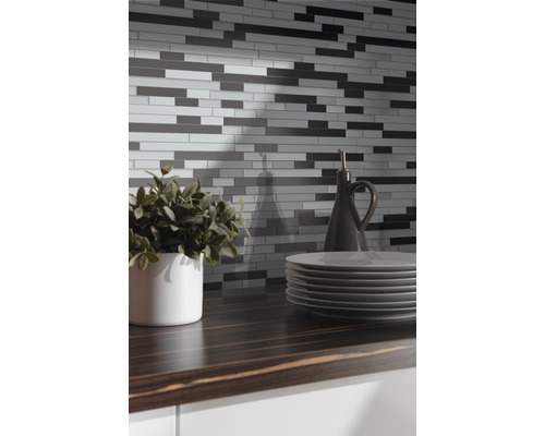 Mozaïektegelwand boven een aanrecht met servies en decoratie