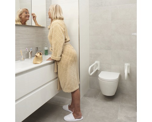 Badkamer met toilet, steunbeugels en een vrouw voor de spiegel
