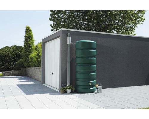 Regenwatertank in de tuin naast een garage met regenpijp.