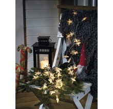 Decoratieve scène met sterrenlichtslinger, lantaarn en kabouter op een kruk.