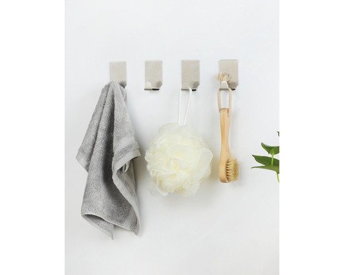 Vier wandhaken met handdoek, badspons en borstel aan een muur
