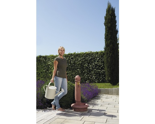 Vrouw met gieter naast een tuin fontein op een terras