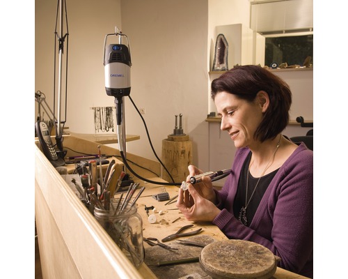 Vrouw werkt met een Dremel multifunctioneel gereedschap aan een werkstuk op een werkbank