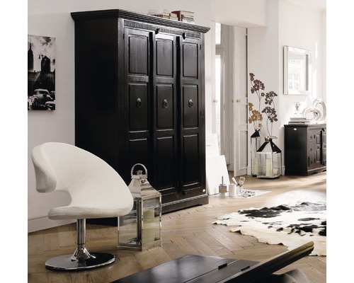 Interieurscène met een zwarte kledingkast, een witte stoel en decoratieve lantaarns in een lichte kamer.