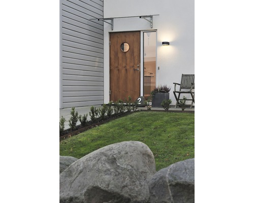 Buitenkant van een modern huis met houten deur, afdak en tuingedeelte