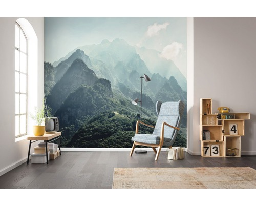 Woonkamer met berglandschap fotobehang, fauteuil, lamp en houten stellingkast