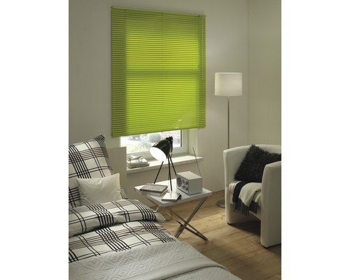 Lichte kamer met groene plissés voor het raam, bed en fauteuil