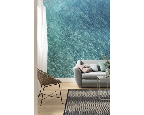 Woonkamer met fotobehang met een zeegezicht, bank, stoel en tapijt