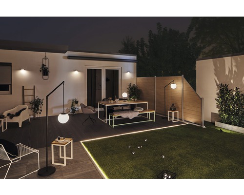 Verlichte tuin met tuinafscheiding, gazon, zitgroep en staande lampen