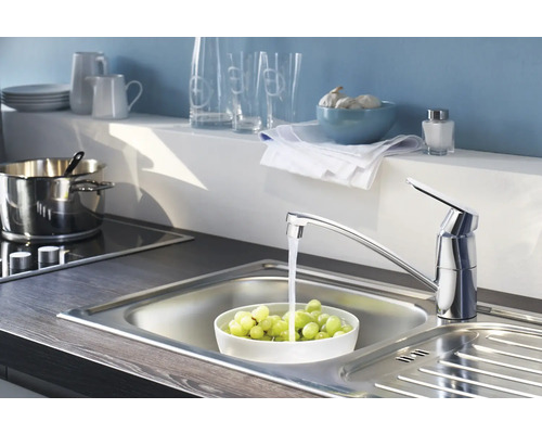 Keukenkraan met stromend water in een roestvrijstalen gootsteen gevuld met druiven in een keuken