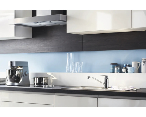 Keukenscène met afzuigkap, keukenmachine, spoelbak en kookplaat in een modern keukenontwerp.