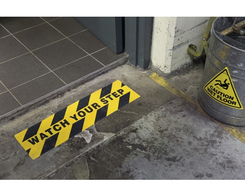 Scene met een bord dat waarschuwt voor een trede en een emmer met een waarschuwing voor natte vloeren.