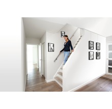 Licht trappenhuis met vrouw op de trap en opgehangen fotolijsten