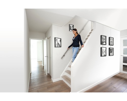 Licht trappenhuis met vrouw op de trap en opgehangen fotolijsten
