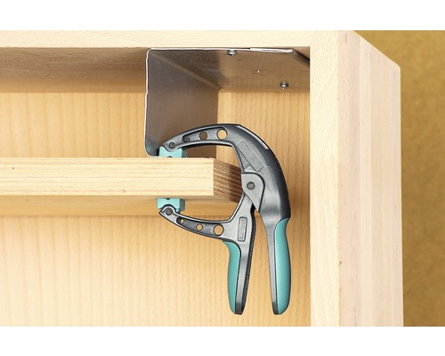 Eenhandklem zet een werkstuk vast aan een meubelstuk.