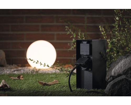 Buitenstopcontact in de tuin met stroomkabel en decoratieve bol