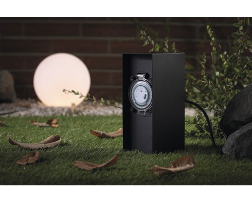 Buitentimer naast een bolvormige lamp in de tuin.