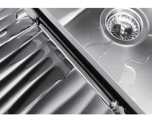 Detailopname van een roestvrijstalen gootsteen met afdruiprek en afvoergarnituur