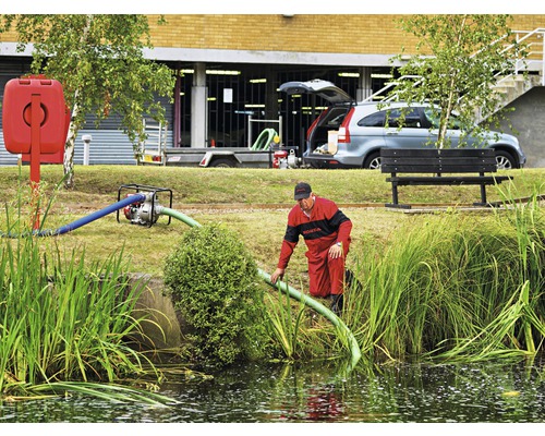 Man met waterpomp aan de rand van de vijver voor afwateringswerkzaamheden.