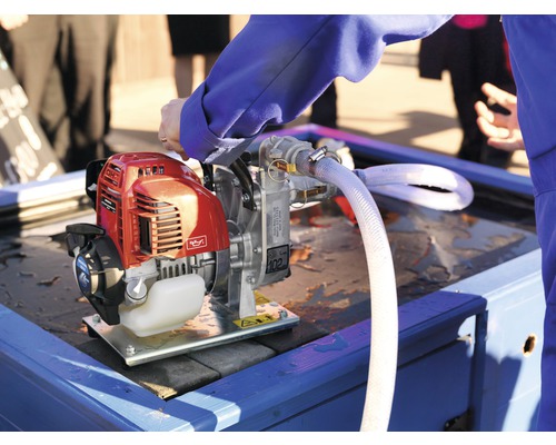 Benzine aangedreven waterpomp met slang op een tafel