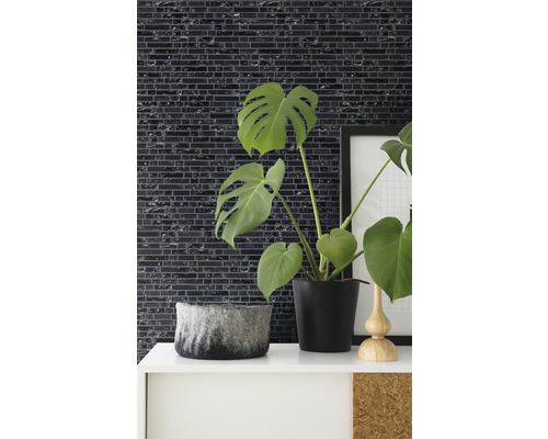 Decoratieve wanddecoratie met mozaïektegels in een kamer met kamerplanten en decoratieve elementen.