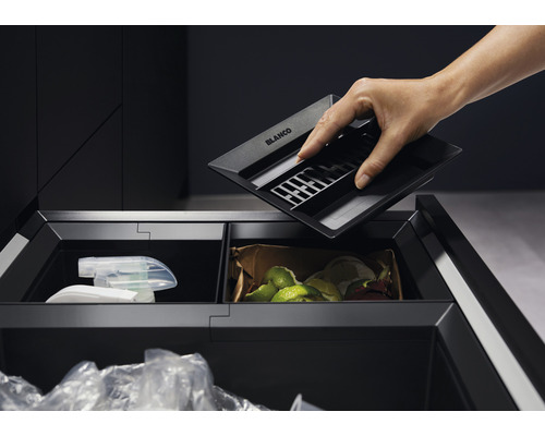 Persoon plaatst Blanco keukenafvalbak in een uittrekkast met afvalscheidingssysteem