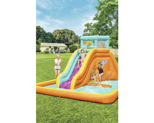 Opblaasbare waterglijbaan met zwembad in de tuin met spelende kinderen.