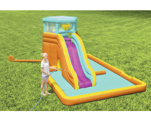 Opblaasbare waterglijbaan met zwembad en dame met waterslang in de tuin