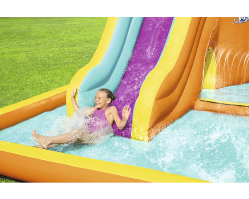 Meisje glijdt van een opblaasbare waterglijbaan in een tuin