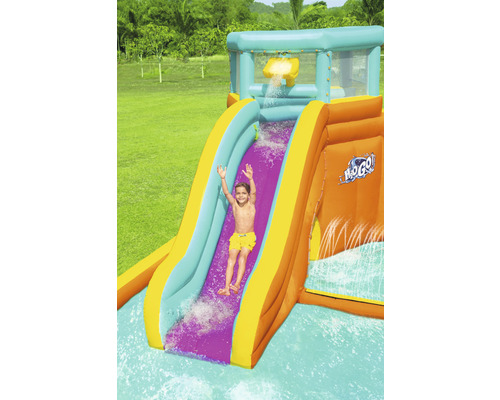 Opblaasbare waterglijbaan met kind dat naar beneden glijdt in de tuin