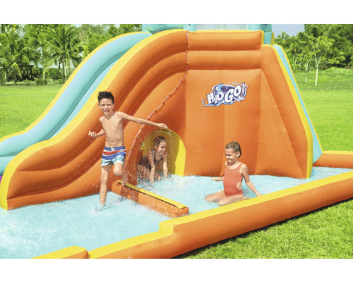 Opblaasbare waterglijbaan met spelende kinderen in de tuin.