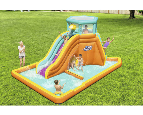 Opblaasbare waterglijbaan met peuterbad en spelende kinderen in de tuin.