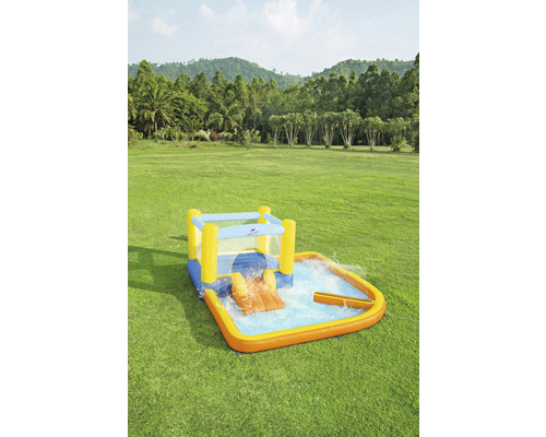 Opblaasbaar kinderzwembad met glijbaan en watersproeier op een groen gazon.