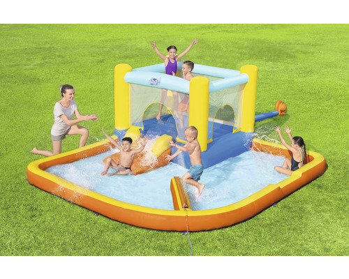 Opblaasbaar waterpark met glijbaan en zwembad in de tuin met spelende kinderen.