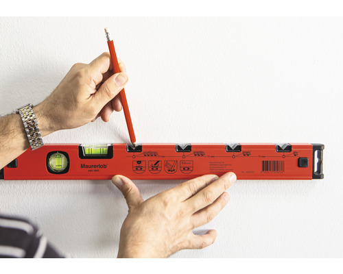 Iemand markeert met een potlood een plek op een muur met een waterpas.