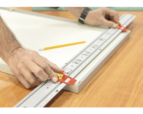 Ambachtsman gebruikt een meetlat met waterpas om een fotolijst uit te lijnen.