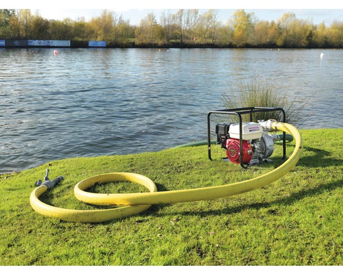 Waterpomp met gele slang aan de oever van een meer